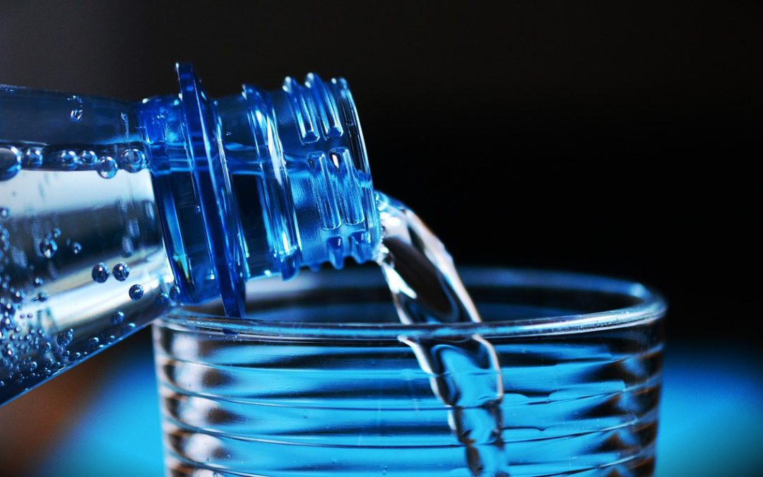 woda nalewana z niebieskiej butelki do szklanki
